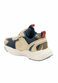 Sneaker beige e blu navy con tessuto strutturato, una cintura regolabile e un logo. Include una suola ammortizzata e un accento rosso sul tallone.