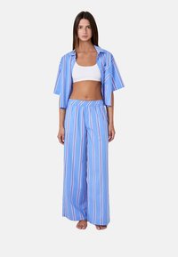 Niebieski zestaw odzieży domowej w paski, składający się z koszulki z krótkim rękawem i spodni o szerokich nogawkach. Wykonany z lekkiego materiału, o luźnym kroju i elastycznym pasie.