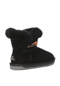 Black suede ankle boots with a soft faux fur cuff, a decorative button closure, and a grey rubber sole. Features a soft texture and rounded shape.
