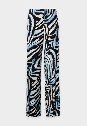 Woman standing with hands on hips wearing black wrap blouse and wide-leg pants with black, white, and blue abstract zebra print.