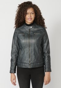 Giubbotto in finta pelle nera con colletto rialzato, zip frontale, due tasche sul petto e ai lati, e dettagli a coste sulle maniche.