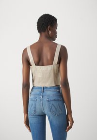 Beige avskåret topp med brede stropper, laget av lin, kombinert med blå skinny jeans med et særegent baklomme-design.