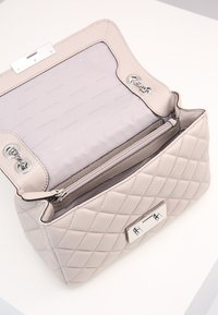 Borsa a tracolla in pelle beige trapuntata con hardware argentato, dotata di una tasca con zip e chiusura a patta, l'interno è foderato in tessuto beige.