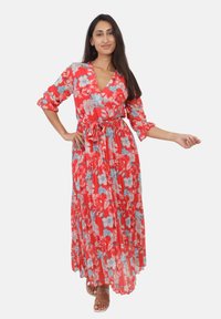 Robe maxi en rouge éclatant avec des motifs floraux en bleu et blanc. Présente un design enveloppant, un col en V, des manches trois-quarts et une taille nouée.
