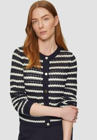 Cardigan navy con motivo a righe bianche, lavorazione a maglia texturizzata, scollo rotondo e bottoni dorati. Design aderente con maniche lunghe.
