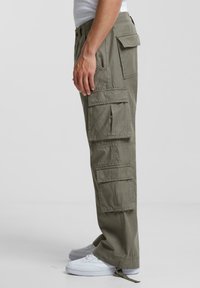 Pantaloni cargo de culoare verde măsliniu cu multiple buzunare mari, croi lejer și manșete ajustabile; fabricați dintr-un material durabil și ușor.