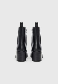 Sorte lær ankle boots med rund tå og stablet hæl. Har sidelukninger og trækstropper for nem påtagning. Glat tekstur.