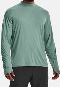 Långärmad skjorta i ljusgrön, tillverkad av mjukt, stretchigt tyg. Har en hög krage och figurnära ärmar, designad för aktiv användning.