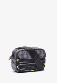Borsa rettangolare compatta in tessuto nero e grigio a motivi, con accenti gialli, chiusura con zip e tracolla regolabile.