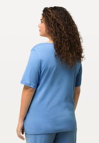 Hellblaues Baumwoll-T-Shirt mit kurzen Ärmeln und rundem Halsausschnitt, mit einem lockeren Schnitt und glatter Textur, von hinten betrachtet.
