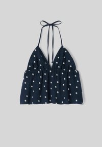 Haut dos nu bleu marine avec motifs de marguerites blanches et fermeture à nouer au niveau du cou, présenté à plat sur un fond gris.