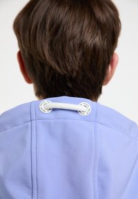 Giacca azzurro chiaro in tessuto morbido, con un accento in corda bianca e occhielli metallici sul collo. Visibili dettagli delle cuciture.
