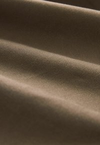 Tissu marron avec une fine texture côtelée présenté en plis doux et en gros plan.