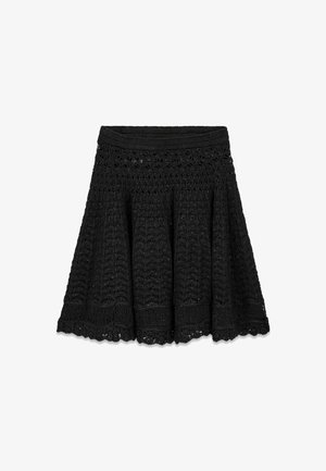Falda negra de punto crochet con forma acampanada en línea A y detalle de borde festoneado.