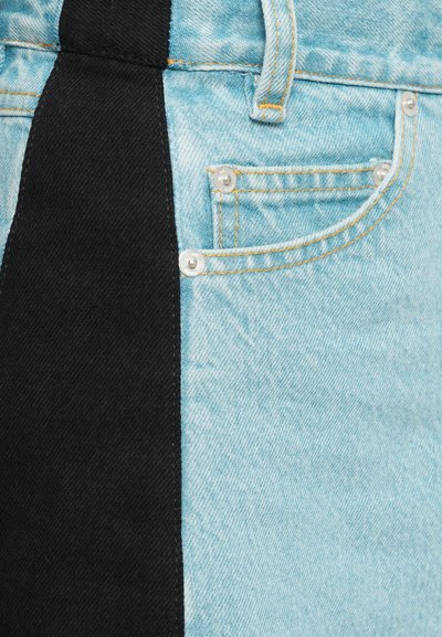 Shorts in denim con una lavatura azzurro chiaro e un pannello in tessuto nero di lato. Presentano una tasca frontale e rivetti in metallo.
