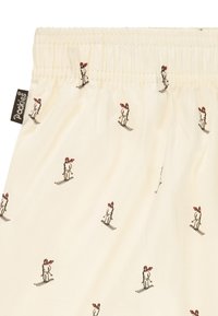 Kremowa tkanina z marszczoną gumką w pasie, zdobiona powtarzającym się wzorem narciarzy w czerwonych szalikach. Miękka tekstura, swobodny design.