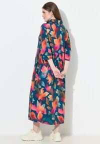 Květované šaty s živými barvami: růžová, oranžová a tyrkysová na tmavě modrém pozadí. Volný střih, s límečkem a tříčtvrtečními rukávy.