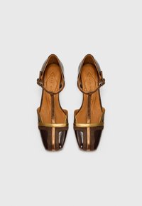 Chaussures en cuir marron avec des accents dorés, ouvertes à l'avant et avec une bride au cheville. Présentent un design en cuir diagonal et une doublure intérieure beige.