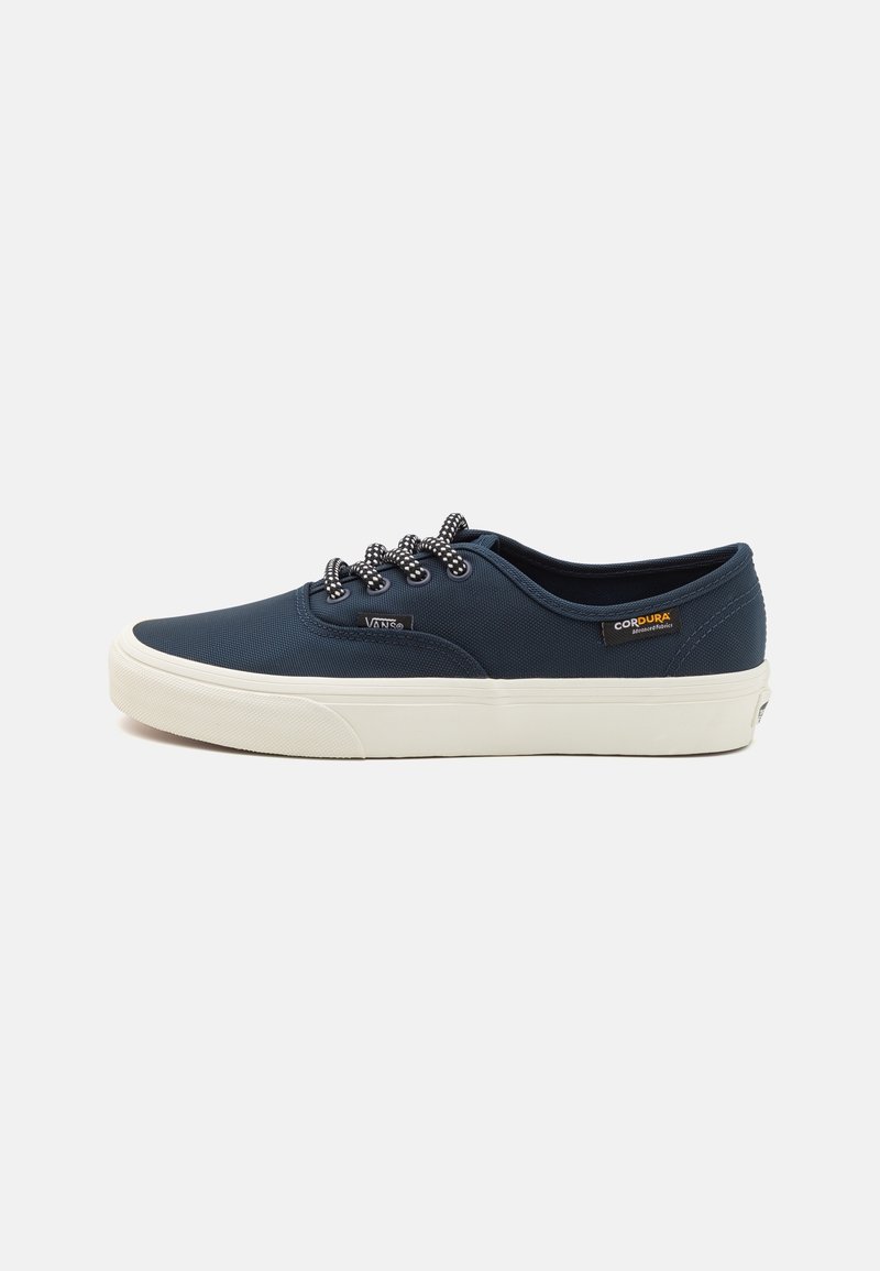 Baskets Vans basses bleu marine avec semelle blanche, lacets noirs et blancs, et étiquette en tissu Cordura sur le côté, vues de profil gauche.
