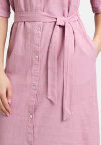 Różowa lniana sukienka z guzikiem z przodu, paskiem w talii i krótkimi rękawami. Gładka tekstura z luźnym krojem w literę A.