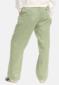 Groene corduroy broek met wijde pijpen, voorzien van verticale ribbels, zijzakken en een achterzak met een klein logo-label.