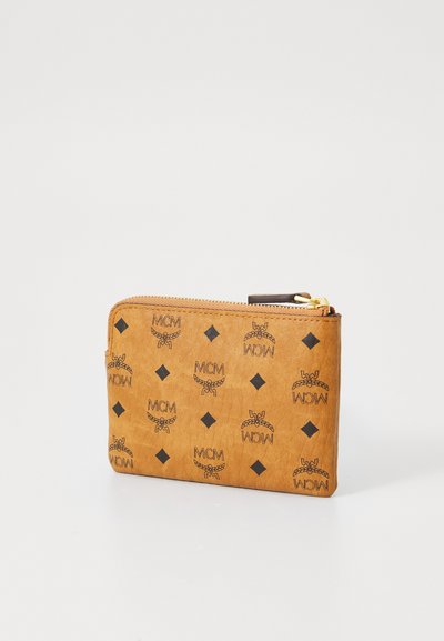 Brun glidelås lommebok med en teksturert overflate, som har gjentatte MCM-logoer og diamantmønstre mot en lys bakgrunn.