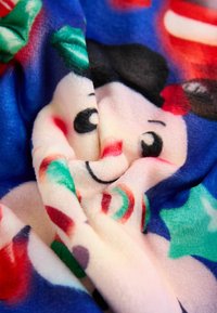Couverture en polaire douce avec un design coloré mettant en scène un personnage souriant, des teintes roses et bleues, et des accents sur le thème des bonbons.