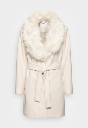 Manteau ceinturé crème avec un grand col en fausse fourrure blanche et duveteuse, manches longues, et longueur mi-cuisse de la marque Vila.