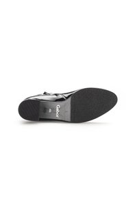 Chaussure en cuir verni noir avec un dessus lisse, un petit talon block, et une semelle en caoutchouc texturé. Présente le logo de la marque et la taille sur la semelle intérieure.