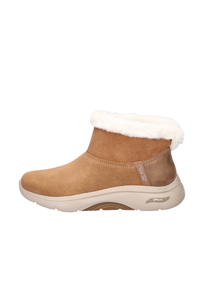 Bruine suède enkelboots met een faux fur voering, ronde neus en beige rubberen zool. Heeft een metalen accent aan de zijkant.