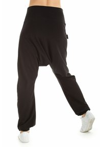 Zwarte harem pants met een brede tailleband, losse pasvorm, elastische boorden bij de enkels en een zachte, lichte stof. Geschikt voor casual wear.
