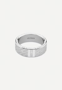 Zilveren ring met een getextureerd ontwerp met een geometrisch patroon en een gepolijst gedeelte gemarkeerd met het "GUESS" logo.