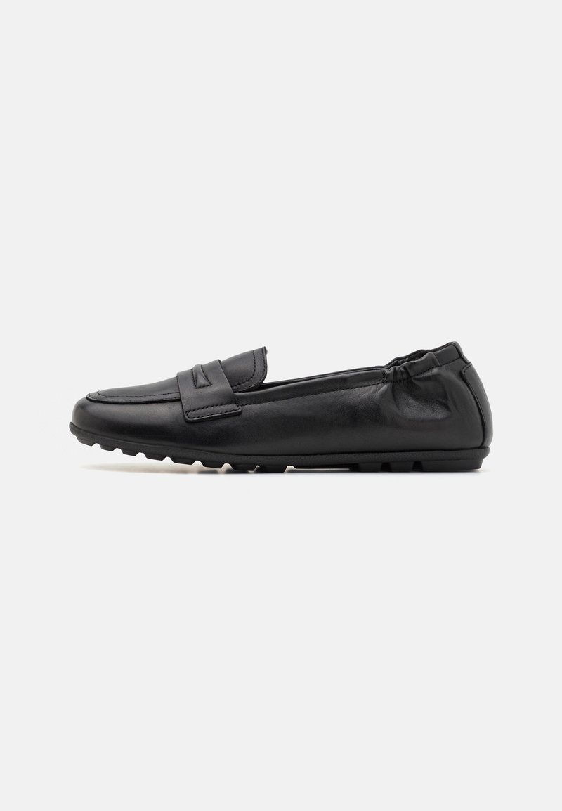 Chaussure penny loafer en cuir noir avec embout arrondi, détails cousus, dos élastiqué et semelle en caoutchouc texturée sur fond blanc.