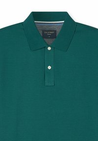 Grünes Poloshirt mit kurzen Ärmeln, zwei weißen Knöpfen und einem umgeschlagenen Kragen, im Nacken mit der Aufschrift "OLYMP CASUAL M" versehen.