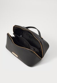 Borsa cosmetica in pelle nera struttura tessuta con zip dorata, dotata di un comparto principale e due tasche interne per l'organizzazione.