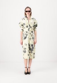 Light yellow floral dress with black patterns, button front, gathered sleeves, and a midi length. Worn with black heels and sunglasses.