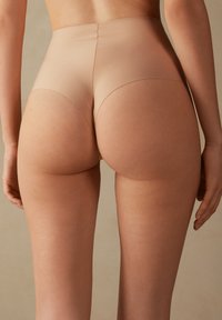 Hoge taille naadloze shapewear in huidskleur, met een gladde, naadloze stof die dekking en een gesculpteerd silhouet biedt. Beschikt over een zachte textuur met minimale naden.
