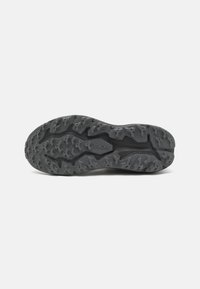 Suela de goma negra con patrón de agarre texturizado, que presenta diferentes diseños de banda de rodadura para tracción y estabilidad. Diseñada para superficies exteriores.
