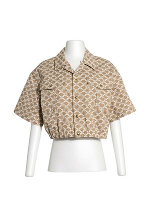 Camisa beige de manga corta recortada con patrón repetitivo marrón claro, botones en el frente, dos bolsillos en el pecho, mostrada en torso de maniquí blanco.