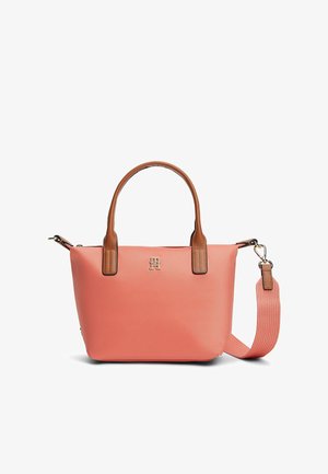 Koralowa torebka z brązowymi uchwytami i odpinanym koralowym paskiem na ramię z tkaniny, z małym metalicznym logo na przodzie.