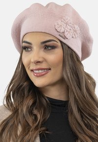 Beret tricotat roz deschis, cu un finisaj texturat, decorat cu trei aplicații de flori cu mărgele și un accent metalic decorativ.