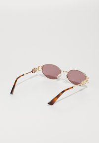 Gafas de sol doradas con lentes ovalados en color rosa, que presentan brazos de carey y hardware decorativo en la unión.