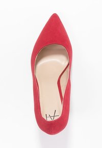 Rode suède pump met een spits toelopende neus, een lage uitsnijding en een gladde binnenkant; subtiel merklogo op de binnenzool.