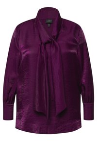 Blusa di raso viola con un fiocco al collo, maniche lunghe con polsini arricciati e una texture liscia e lucida.