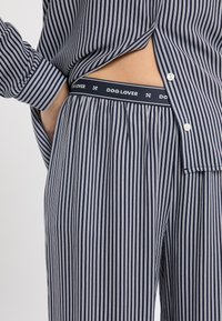 Granatowo-biały zestaw piżam w paski z koszulą zapinaną na guziki i elastycznym pasem, z napisem „DOG LOVER”. Miękka tkanina o luźnym kroju.