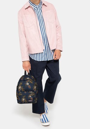 Veste en daim rose clair, chemise rayée bleue et blanche, pantalon navy, sac à dos floral navy à motifs, et chaussures à enfiler rayées bleues et blanches.