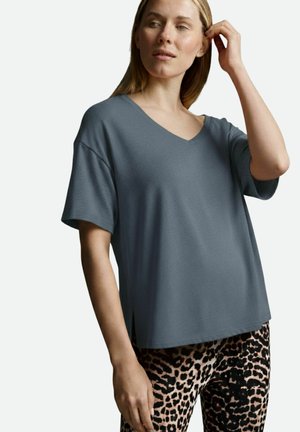 Grey, short-sleeved V-neck t-shirt with a relaxed fit and side slits, paired with leopard print leggings. Smooth fabric texture.
