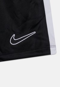 Svarta sportshorts med en vit sydd Nike-logotyp, med en kontrasterande grå sidopanel och ett slätt, lätt tyg.
