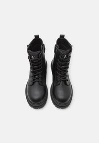Black leather ankle boots with a smooth finish, featuring lace-up design, side zipper, and textured sole for grip. Logo detail on tongue.
