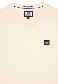 Tricou din bumbac de culoare piersiciu deschis, cu gât rotund, având o mică etichetă din material negru pe partea stângă a pieptului. Textură fină.